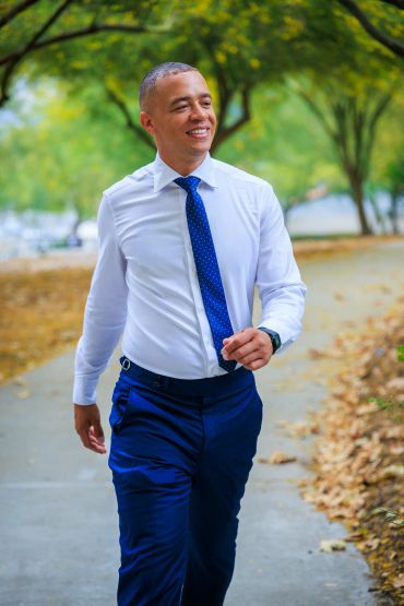Man walking outside in formal attire, smiling.