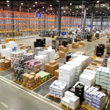 Warehouse filled with stacked pallets and boxes in an organized layout.