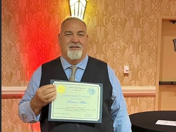Man proudly holding an achievement award certificate indoors.