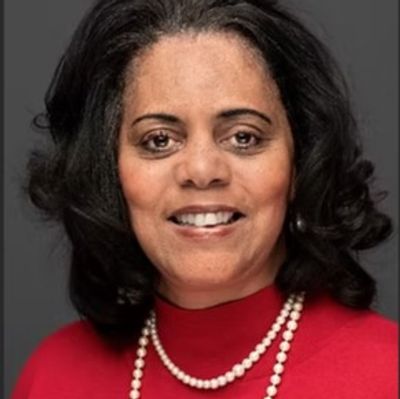 Portrait of a smiling woman in a red top and pearl necklace.