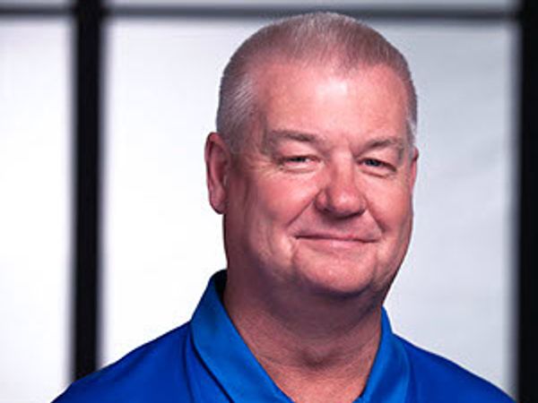 Smiling middle-aged man in a blue polo shirt.