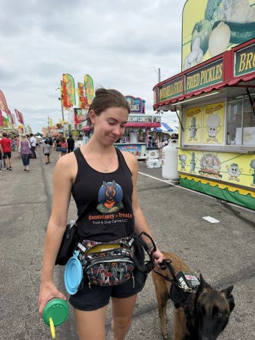 A woman walks a dog at a fairground.