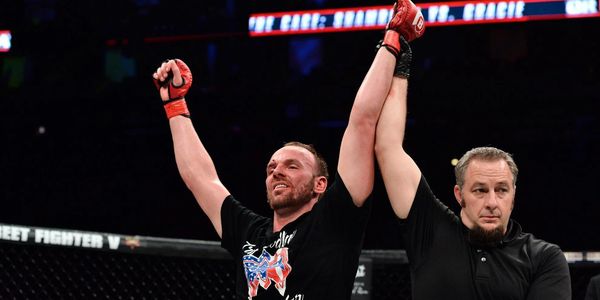 MMA fighter celebrating victory with referee raising his arm.