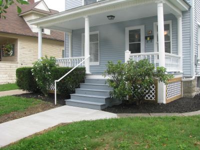 Front porch with stairs and bushes.