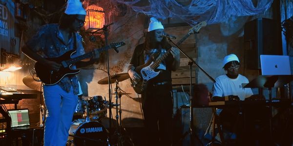 A band performs live in a dimly lit, cozy venue with Halloween decorations.