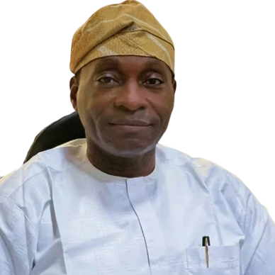 Man in traditional white attire and brown cap sitting with hands clasped.
