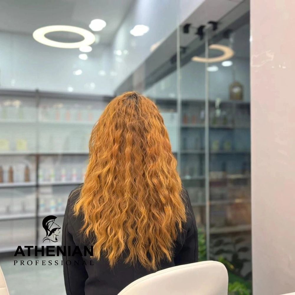 Woman with long, wavy, golden hair sitting in a salon chair.