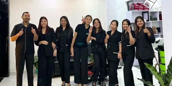 A group of eight people posing in a modern, well-lit room, all wearing black outfits.
