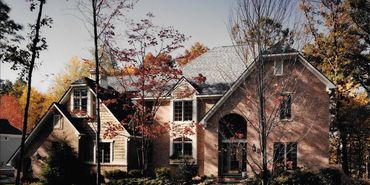 Modern French Traditional custom home exterior with brick and stone by Kraus Plans