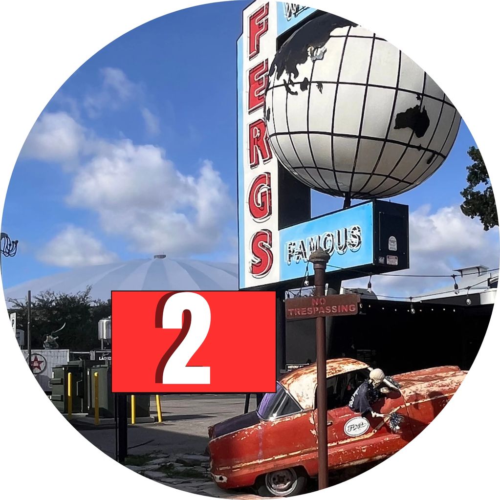 Vintage car and globe sign at Ferg's Famous with a clear blue sky.