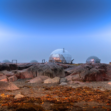 Group of glamping geodesic domes on rocky shoreline