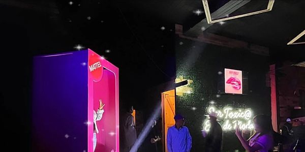 Mattel Barbie box display with people in a dark room and neon lights.