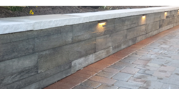 Retaining wall covered with wood like planks and stone caps.