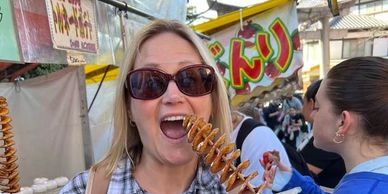 Woman enjoying a spiral potato snack at an outdoor market.