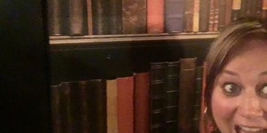 Woman smiling in front of a bookshelf filled with old books.