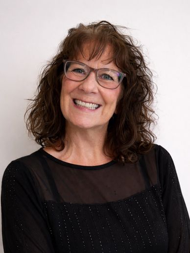 Smiling woman with glasses and curly hair.