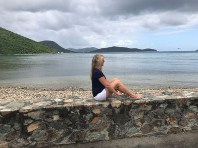 Woman sitting on a stone wall by the sea.