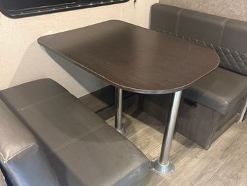 Compact dining area with dark wooden table and grey cushioned seats.