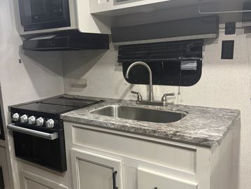Compact kitchen setup with stove and sink.