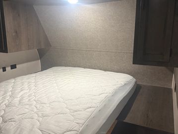 Cozy bed with a white mattress in a compact wooden room.