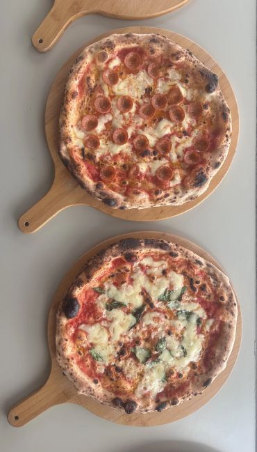Two rustic pizzas on wooden serving boards.