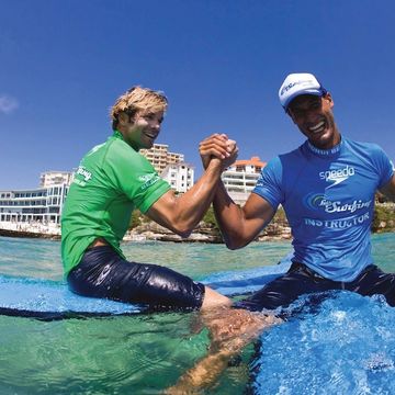 Two surfers shaking hands in the surf on Bondi beach