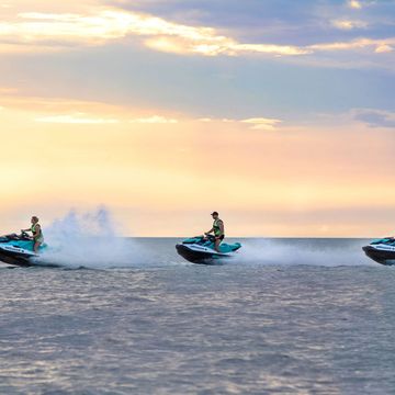 Three jetskis riding at sunset