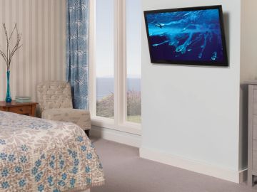 Cozy bedroom with scenic window view and wall-mounted TV.