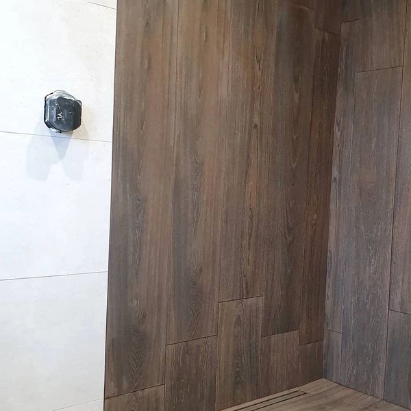 A wet room with wall and floor wood effect tiles.