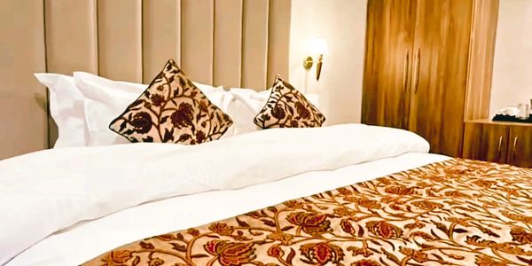 Cozy bedroom with floral-patterned bedding and wooden wardrobe.