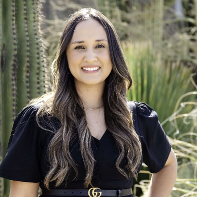 Smiling woman with long hair standing outdoors near cacti.