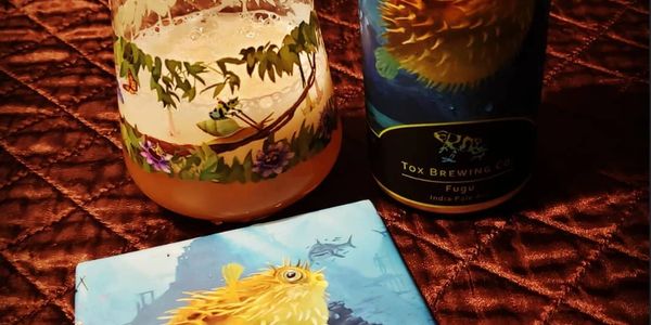 A glass of Fugu beer and Fugu beer can and Fugu coaster.