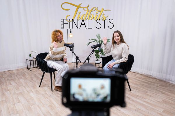 Two women hosting a podcast in a studio with microphones.