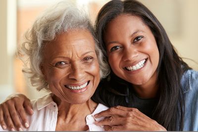 Two women smiling warmly, showing a close bond.