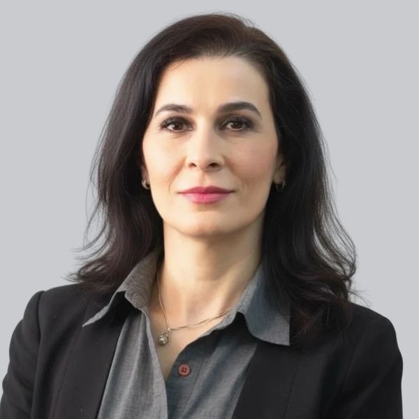 Confident woman in professional attire with dark hair and a neutral background.