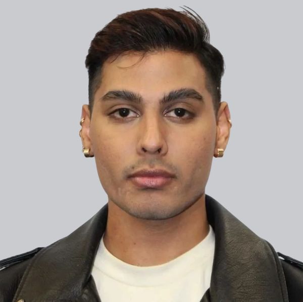 Portrait of a man with earrings in a black leather jacket and white shirt.