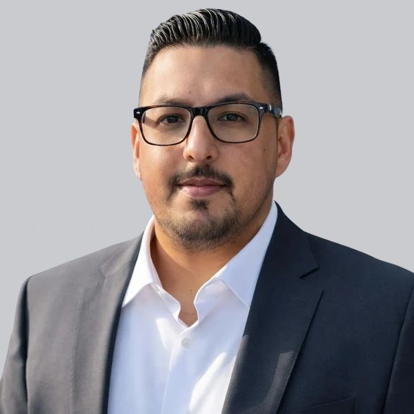 Professional man in glasses wearing a dark blazer and white shirt.