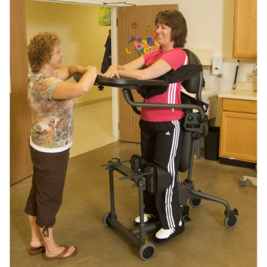 A lady in a pink top standing in an EasyStand Evolv fitted with a shadow tray and swing away front