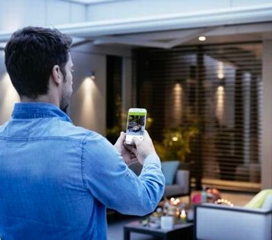 A person controlling their blinds using a mobile phone and Somfy Motorised products.
