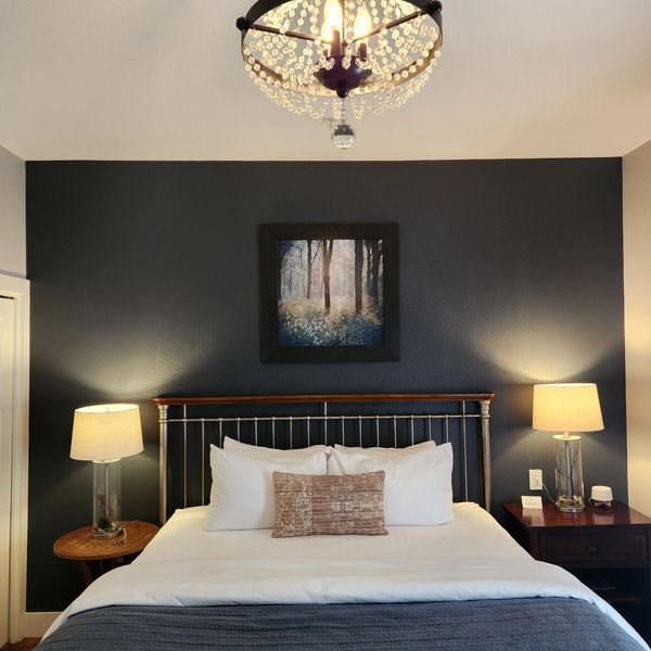 Cozy bedroom with dark blue accent wall and warm lighting.