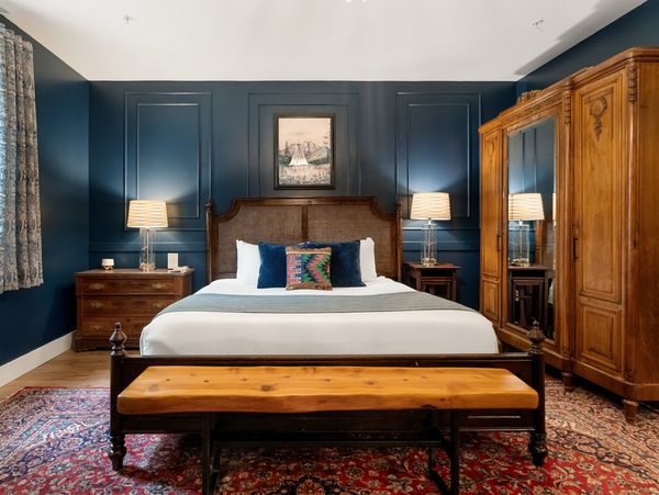 Cozy bedroom with blue walls, wooden furniture, and warm lighting.