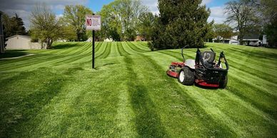 A lawn mower on freshly mowed grass with a no trespassing sign.