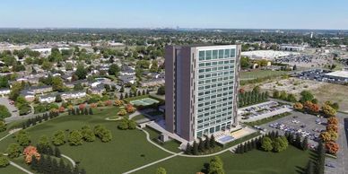 A tall office building surrounded by greenery and parking lots.