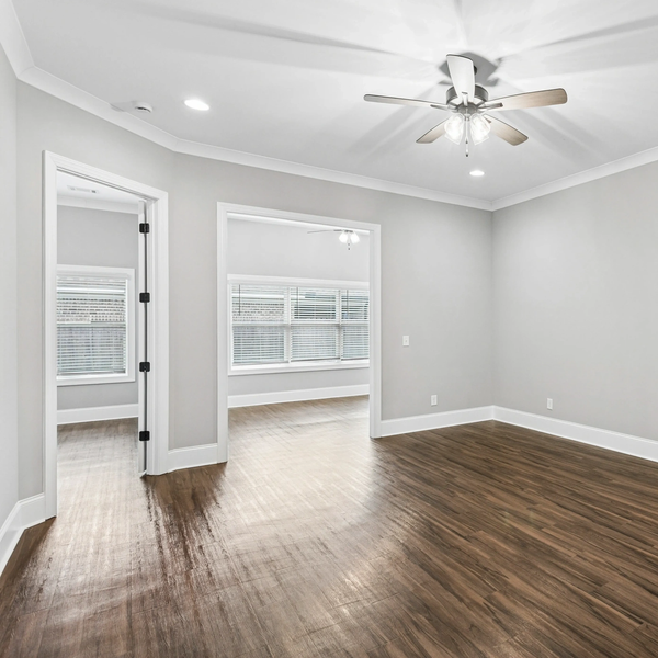 Empty modern room with wood flooring and ceiling fan.