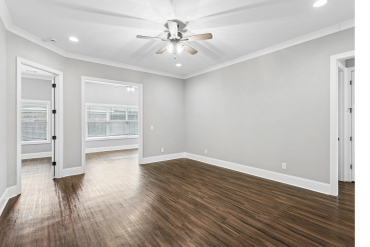 Empty room with wood-like flooring and ceiling fan.