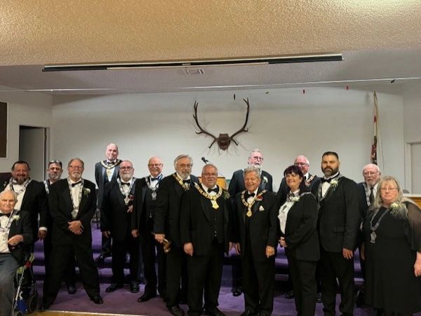 Group of formally dressed people in a room with deer antlers on the wall.