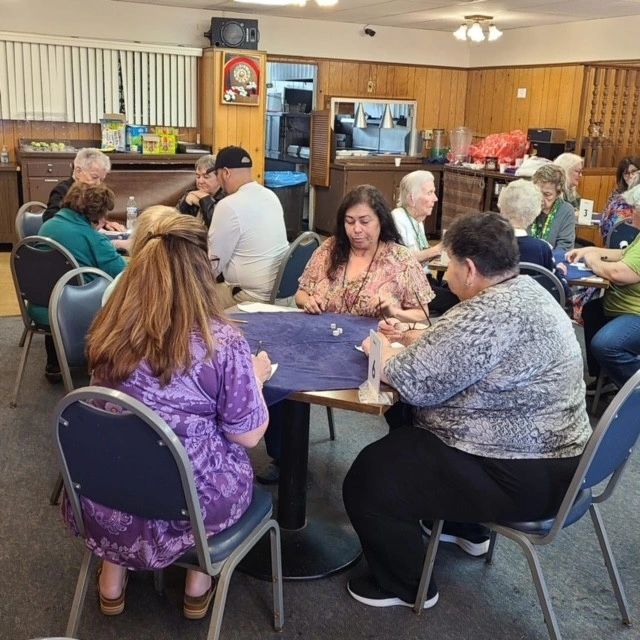 Group of people playing a dice game in a community room.