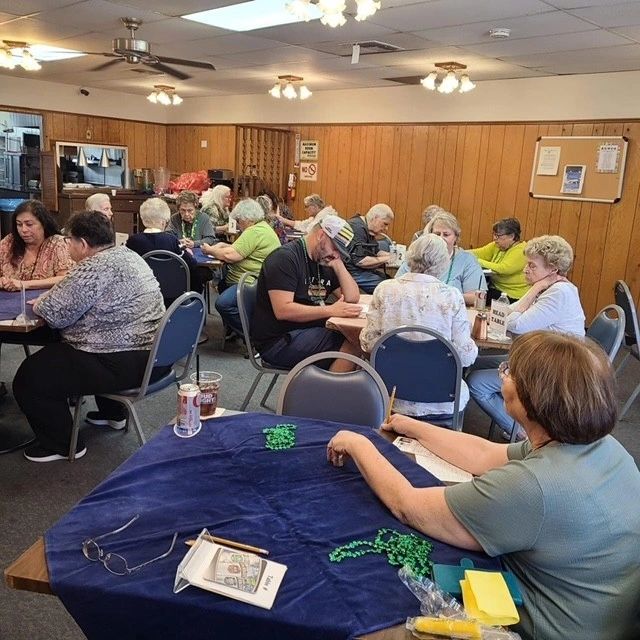 A group of elderly people playing bingo in a community room.