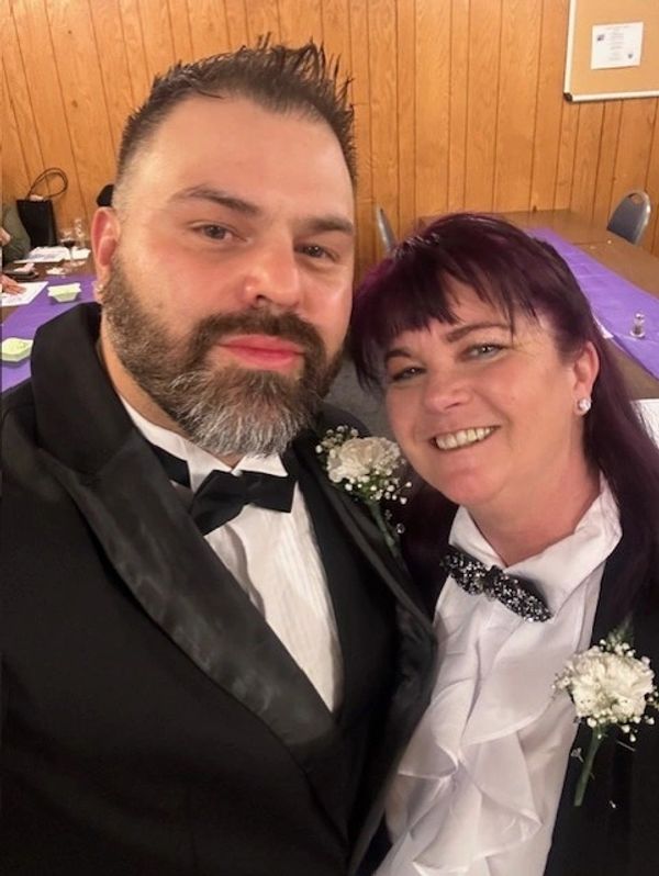 Couple dressed in formal attire with floral boutonnieres.