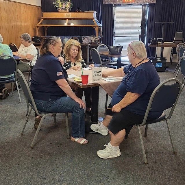 Three women sitting around a table labeled 'Head Table' engaged in discussion.